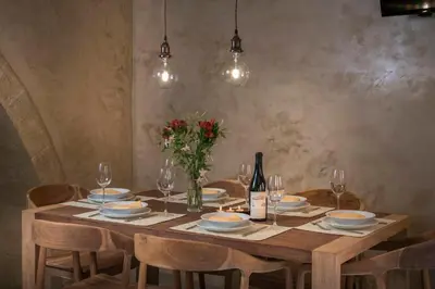 a wooden table with a bottle of wine and a vase of flowers at Neoria Houses in Chania Town