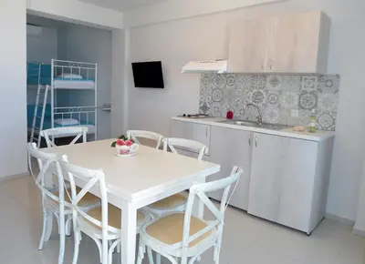 a kitchen with a white table and chairs and a sink at Petrakis sunset in Palaiochóra