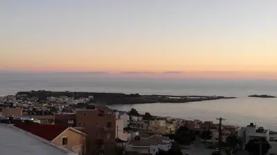 a view of a city and the ocean at sunset at Petrakis sunset in Palaiochóra