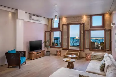 a living room with a couch and a tv and windows at Residenza Vranas Boutique Hotel in Chania Town