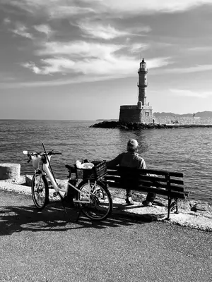 a man sitting on a bench in front of a lighthouse at Casa Sabbionara in Chania Town