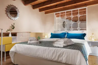 a bedroom with a large bed with blue pillows on it at Aeria Apartments in Chania Town