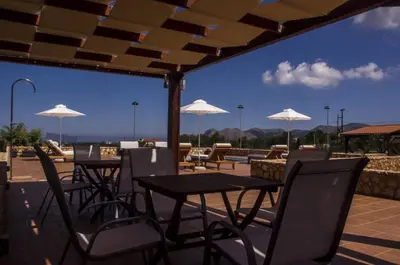 a patio with tables and chairs and white umbrellas at Horizon Villa Kampani in Kambánion