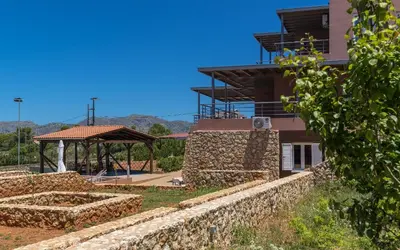 a building with a stone retaining wall and a pavilion at Horizon Villa Kampani in Kambánion