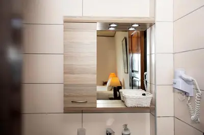 a mirror on a wall in a bathroom with a lamp at Argo Rooms-Papadakis in Kissamos