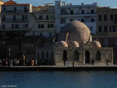 a group of people standing around a building next to the water at Old Town Apartments in Chania Town