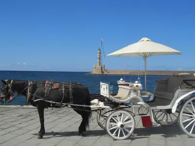 a horse drawn carriage with a lighthouse in the background at Economy Studio Apartments in Chania Town