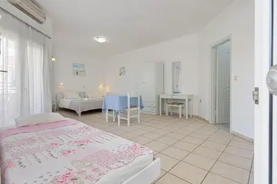 a bedroom with two beds and a table and a desk at Marias Studios & Apartments in Platanias in Plataniás