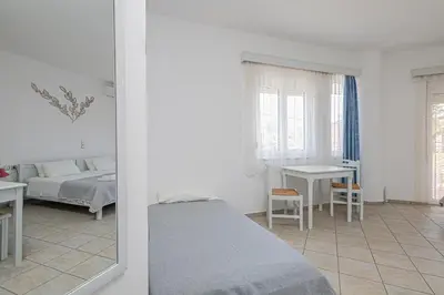 a bedroom with a bed and a table and a mirror at Marias Studios & Apartments in Platanias in Plataniás
