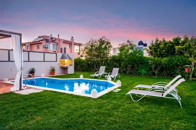 a backyard with a swimming pool and chairs and a house at Dream Villa in Kambánion
