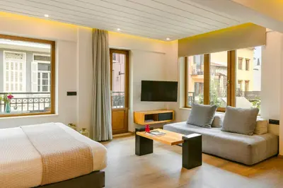 a bedroom with a bed and a couch and a tv at Querini Luxury Suites in Chania Town