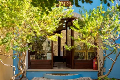 an entrance to a building with trees in the foreground at Iliopetra in Douliana