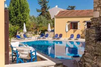 a swimming pool with blue chairs and umbrellas at Iliopetra in Douliana