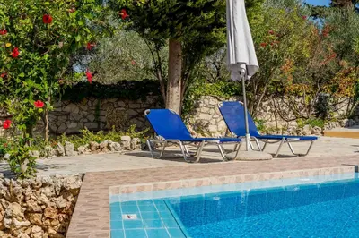 two chairs and an umbrella next to a swimming pool at Iliopetra in Douliana