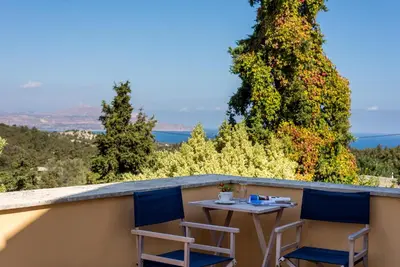 a table and two chairs on a balcony with trees at Iliopetra in Douliana