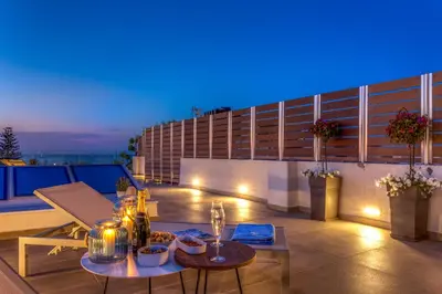 a rooftop patio with two tables on a building at night at Angels Suites in Plataniás