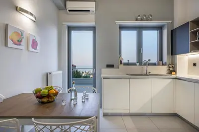 a kitchen with white cabinets and a wooden table at Elysium Seaview Oasis in Kato Galatas