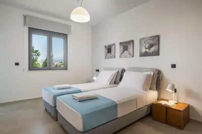 a white bedroom with two beds and a window at Elysium Seaview Oasis in Kato Galatas