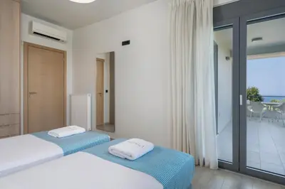 two beds in a bedroom with a view of the ocean at Elysium Seaview Oasis in Kato Galatas