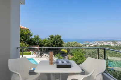 a balcony with a table and chairs and a pool at Elysium Seaview Oasis in Kato Galatas