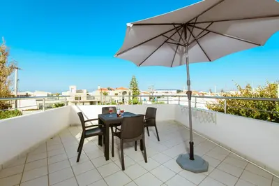 a table and chairs on a balcony with an umbrella at Gelina Apartments in Plataniás
