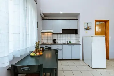a kitchen with a black table and a refrigerator at Gelina Apartments in Plataniás