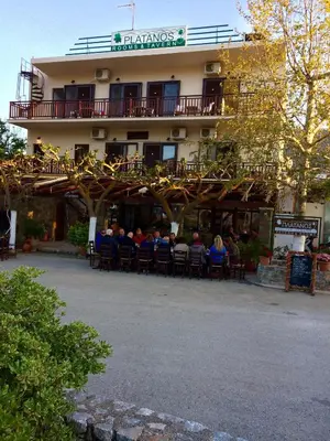 a group of people sitting in chairs in front of a building at Platanos Rooms in Anopoli Sfakion