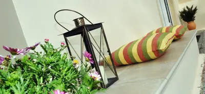 a black lantern sitting on a counter next to flowers at Villa Lakki Heated round pool Jacuzzi in Lákkoi