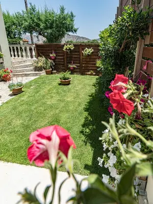 a yard with red flowers and a fence at Big Blue Villa in Kisamos, 10 meters from Sea in Kissamos
