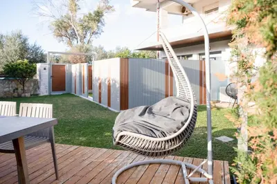a hammock in a yard with a table and a patio at Glaros Casa Verde - Cozy flat with Garden near Beach in Kato Daratso