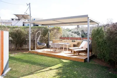 a wooden deck with a canopy in a backyard at Glaros Casa Verde - Cozy flat with Garden near Beach in Kato Daratso