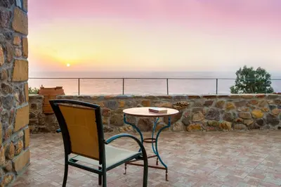 a table and a chair on a patio with the ocean at Villa Kimothoe with Private Pool, only 20 min to Elafonissi Beach in AmigdhalokeFálion