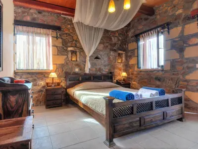 a bedroom with a bed in a room with stone walls at Villa Kimothoe with Private Pool, only 20 min to Elafonissi Beach in AmigdhalokeFálion