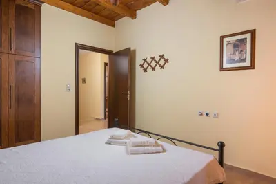 a bedroom with a bed with white sheets and a mirror at Adam Villas in Falasarna