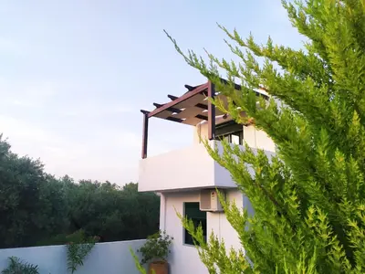 a house with a fence and a tree at Sunny Villa in Kissamos