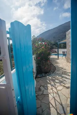 a blue door leading to a pool with flowers at Villa Afou in Afráta