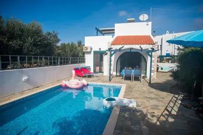 a swimming pool with a pink inflatable raft in front of a house at Villa Afou in Afráta