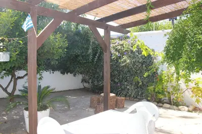 a wooden pergola with a white chair under it at Tasos Cottages in Gerani Chanion