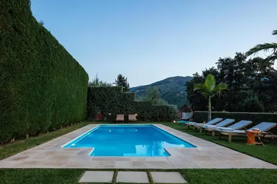 a swimming pool with two lounge chairs next to a hedge at Epimenidis House in Sinoikismós Kondoudhianá