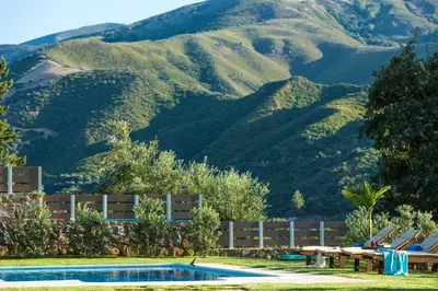 a pool with chairs and mountains in the background at Epimenidis House in Sinoikismós Kondoudhianá