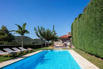 a pool with chairs and a hedge next to a house at Epimenidis House in Sinoikismós Kondoudhianá