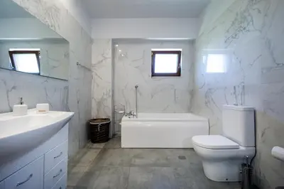 a white bathroom with a tub and a toilet and a sink at Iridanos Villa in Kissamos