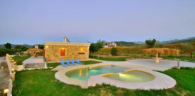 a backyard with a pool with chairs and a building at Iridanos Villa in Kissamos