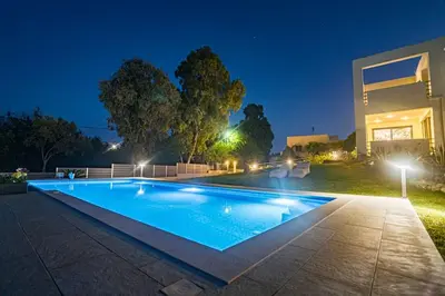 a swimming pool in front of a house at night at Villa Detoro in Kambánion