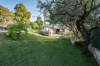 a park with a tree and a bench in the grass at Villa Detoro in Kambánion