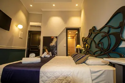 a bedroom with a large bed with a woman sitting on it at Elia Palatino Hotel in Chania Town