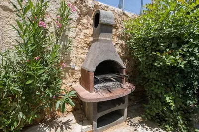 a stone oven sitting next to some bushes at Villa Kourouni in Stalos