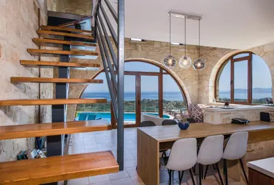 a kitchen and dining room with a spiral staircase in a house at Villa Kourouni in Stalos
