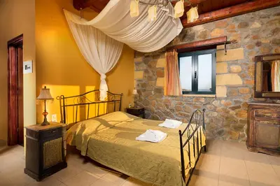 a bedroom with a bed and a stone wall at Sea-Sunset Views Villa Lefkothea with Private Pool near Elafonissi in AmigdhalokeFálion