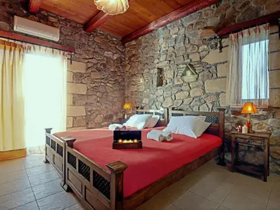 a bedroom with a large bed with a stone wall at Sea-Sunset Views Villa Lefkothea with Private Pool near Elafonissi in AmigdhalokeFálion